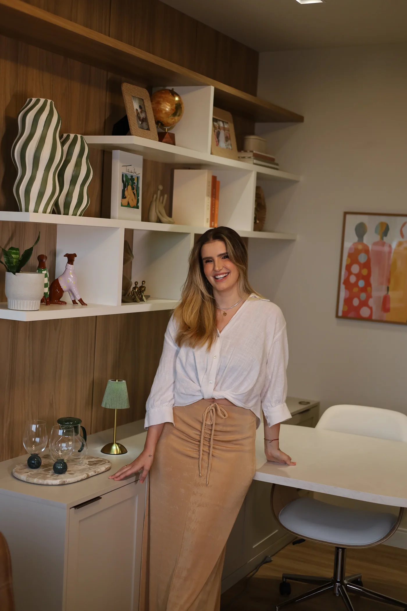 Isabella em pé, ao lado das estantes do consultório